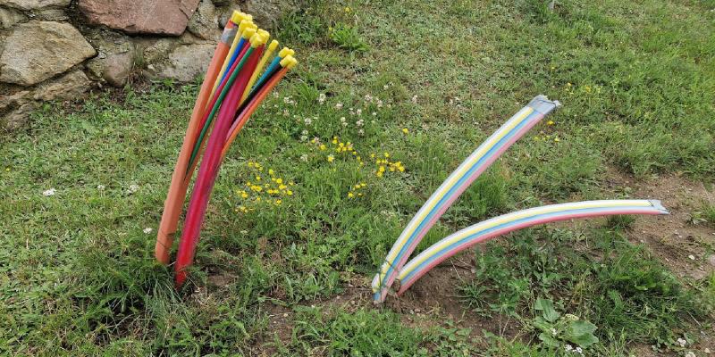 Mehrere Bündel von Glasfaser-Leerrohren schauen aus einer Grasfläche